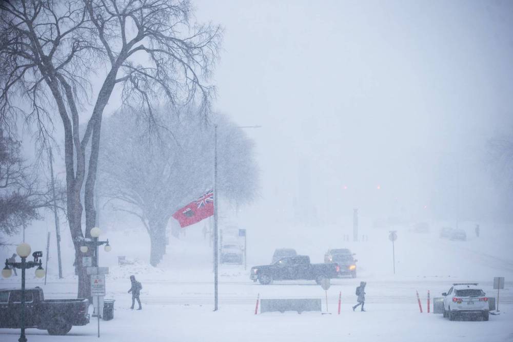 MIKAELA MACKENZIE / FREE PRESS Pedestrians and cars navigate snowy conditions on Broadway on Wednesday as a winter storm moves into the region.