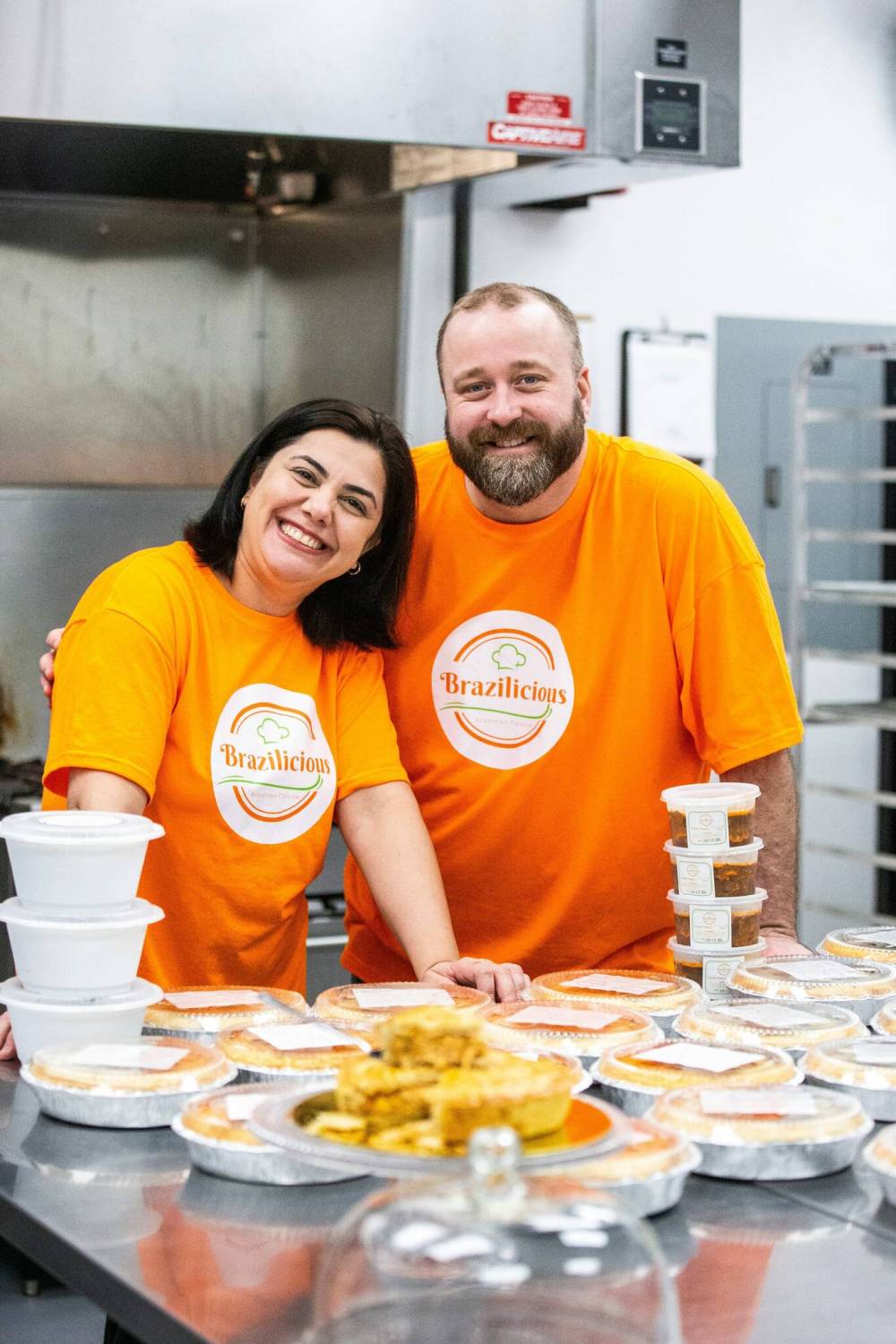 MIKAELA MACKENZIE / FREE PRESS
                                Brazilicious owners Marli Cordella (left) and Giuliano Roveri serve up some freshly made empadão chicken pies and other frozen dishes in their commercial kitchen in Winnipeg.