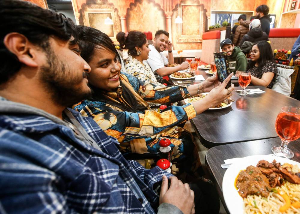 JOHN WOODS / FREE PRESS
Fariha Peu and Zafrul Hasan Shuvo, with their family and friends, take a photo of themselves at an iftar buffet at the Barbecue Hut.