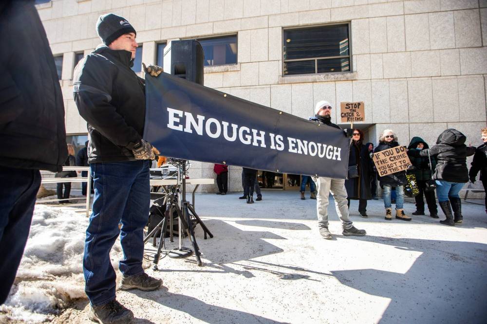 MIKAELA MACKENZIE / FREE PRESS Lee Seiler (left) and Terry G. (no last name given) hold a banner at a rally calling for an end to the catch and release justice system outside of the Law Courts in Winnipeg on Friday, March 22, 2024.