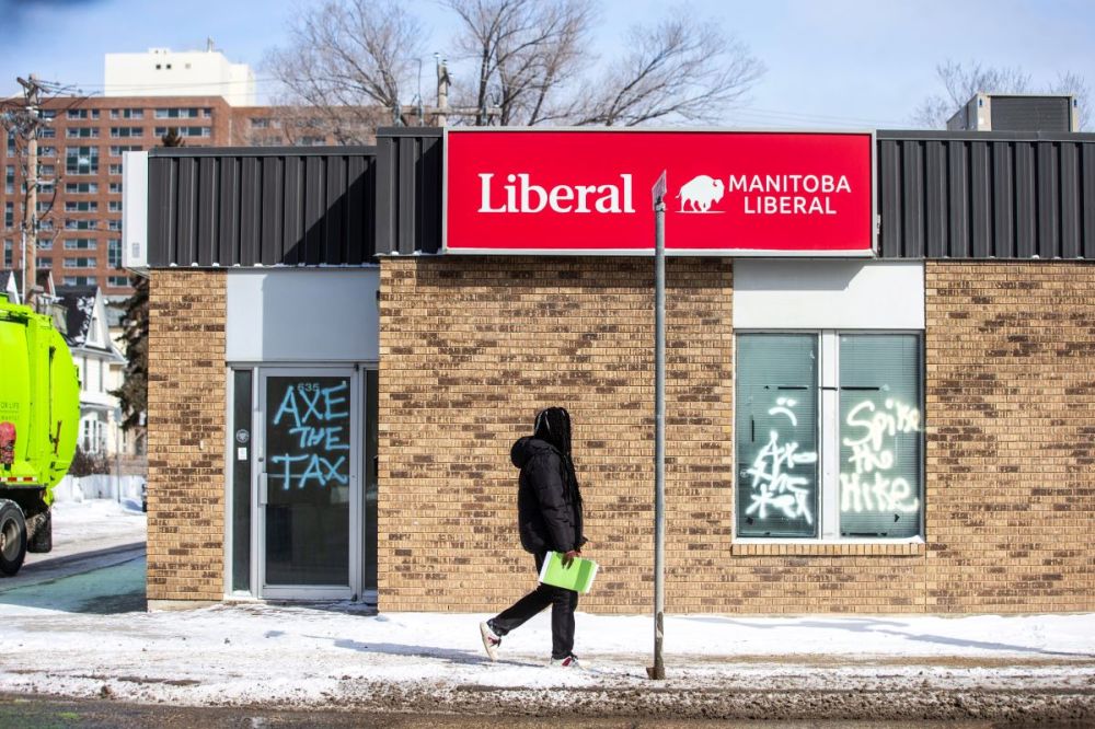 MIKAELA MACKENZIE / FREE PRESS Graffiti reads “axe the tax” and “spike the hike” on the windows and doors of the Manitoba Liberal Party office on Broadway on Wednesday, March 27, 2024.