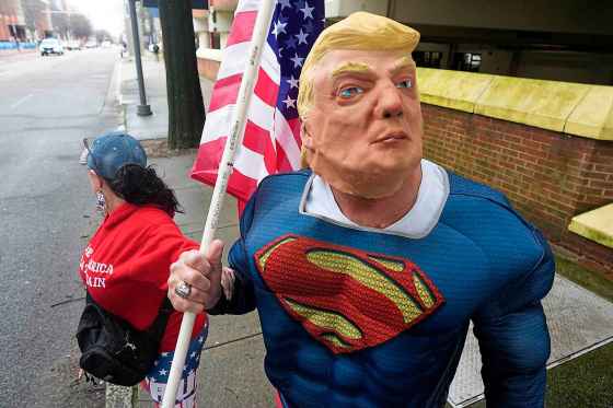 A supporter wears a Trump mask ahead of a campaign rally with the Republican presidential candidate earlier this month. A reader complains he's seen too much of his face — but it's impossible for media to ignore. (Steve Helber / The Associated Press files)