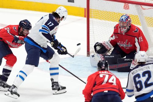 Winnipeg Jets center Adam Lowry (17) shoots against Washington Capitals goaltender Charlie Lindgren (79) in the third period of an NHL hockey game, Sunday, March 24, 2024, in Washington. (AP Photo/Mark Schiefelbein)
