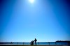 A total solar eclipse is set to fall over parts of Canada, gathering massive crowds in its path who hope to catch a glimpse of the rare celestial event. A blue sky shines below the sun as a person walks with an infant along the shores of Lake Ontario, a day before a total solar eclipse will be visible in Kingston, Ont., Sunday, April 7, 2024. THE CANADIAN PRESS/Justin Tang