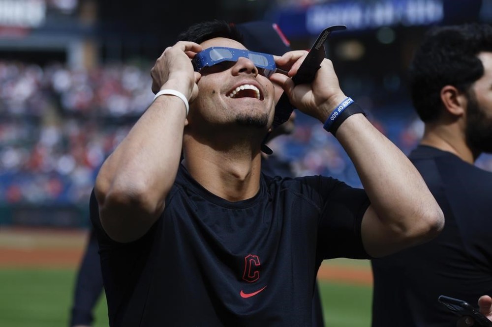 Cleveland Guardians second baseman Andrés Giménez uses special glasses to watch the total solar eclipse, Monday, April 8, 2024, in Cleveland. (AP Photo/Ron Schwane)