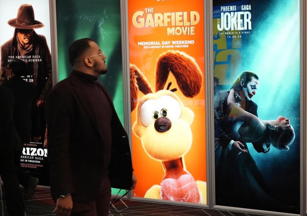 An attendee walks past advertisements for upcoming films including