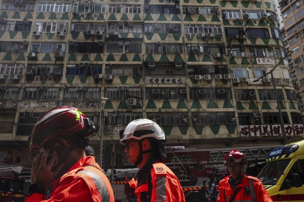 Firefighters walk past a building called New Lucky House where a fire started in Hong Kong, Wednesday, April 10, 2024. (AP Photo/Louise Delmotte)