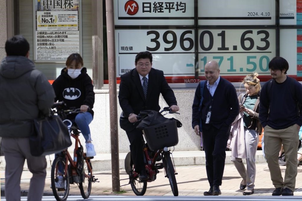 People move past an electronic stock board showing Japan's Nikkei 225 index at a securities firm Wednesday, April 10, 2024 in Tokyo. (AP Photo/Shuji Kajiyama)