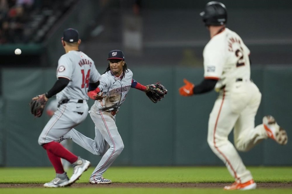 Washington Nationals shortstop CJ Abrams, center, tosses the ball to second baseman Ildemaro Vargas (14) to force out San Francisco Giants' Matt Chapman at second during the sixth inning of a baseball game Tuesday, April 9, 2024, in San Francisco. (AP Photo/Godofredo A. Vásquez)
