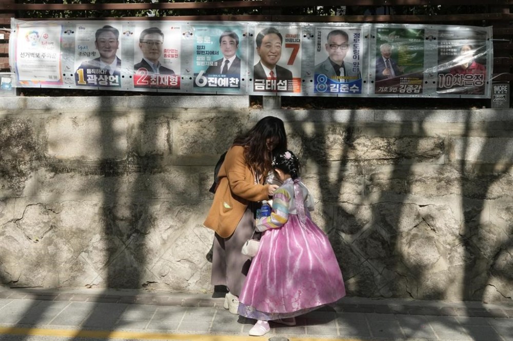 A mother and her daughter stand under posters of candidates running for the upcoming parliamentary election in Seoul, South Korea, Tuesday, April 9 2024. The parliamentary election will be held on April 10. (AP Photo/Ahn Young-joon)