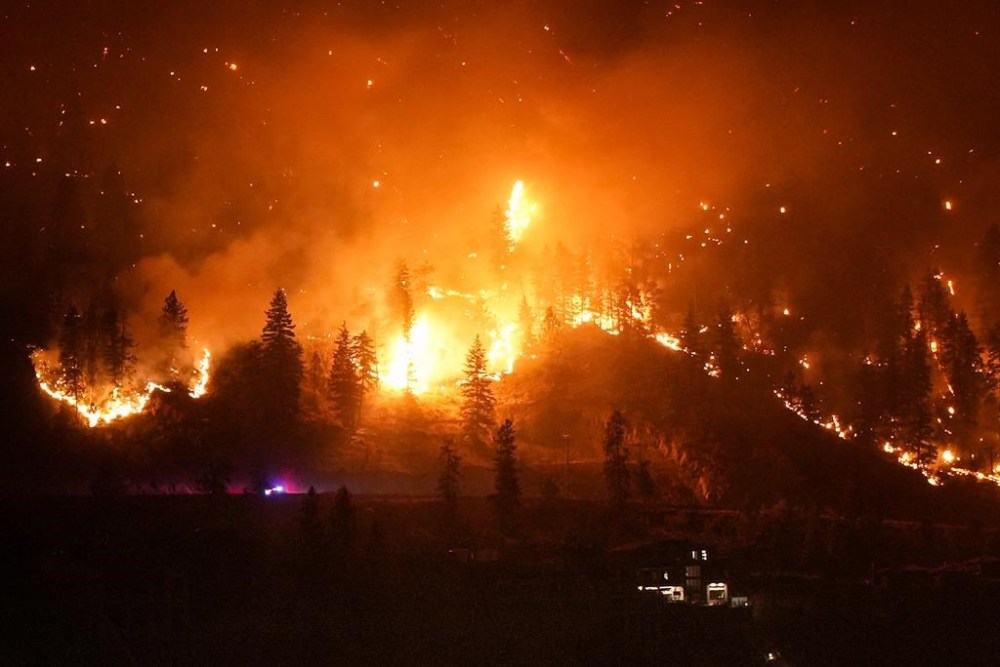 The McDougall Creek wildfire burns on the mountainside above a lakefront home, in West Kelowna, B.C., on August 18, 2023. As Canada looks ahead to what experts fear could be another devastating wildfire season, fire chiefs are worried about the dwindling number of volunteer firefighters available to combat the rising threat. THE CANADIAN PRESS/Darryl Dyck