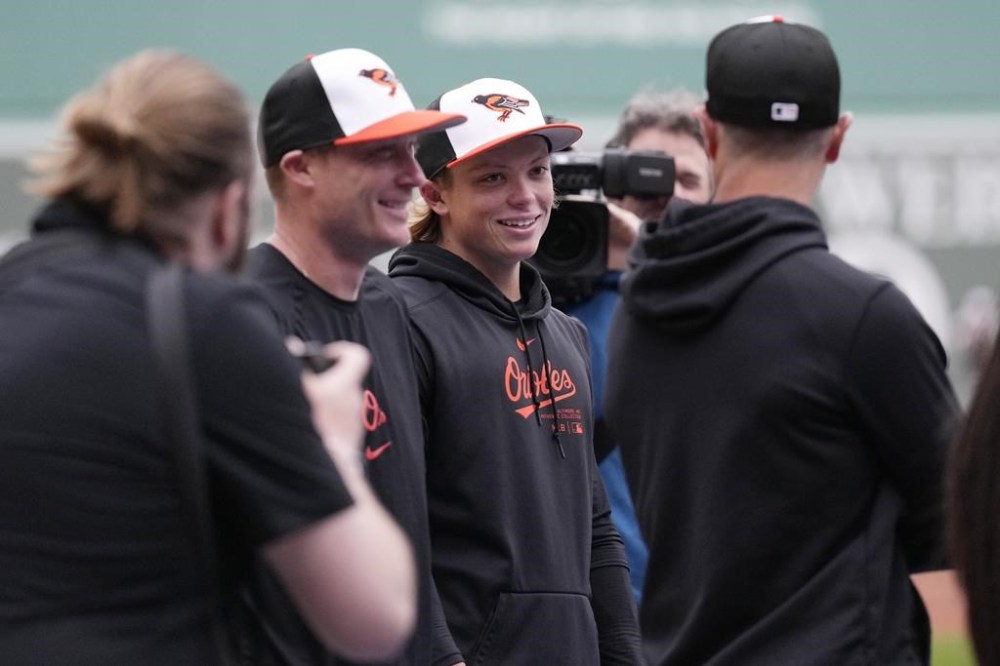 Baltimore Orioles' Jackson Holliday, second from right, smiles while surrounded by cameras and teammates during batting practice prior to his first major league baseball game against the Boston Red Sox, Wednesday, April 10, 2024, in Boston. Holliday, the son of seven-time All-Star Matt Holliday, is schedule to play second base in Wednesday game. (AP Photo/Charles Krupa)