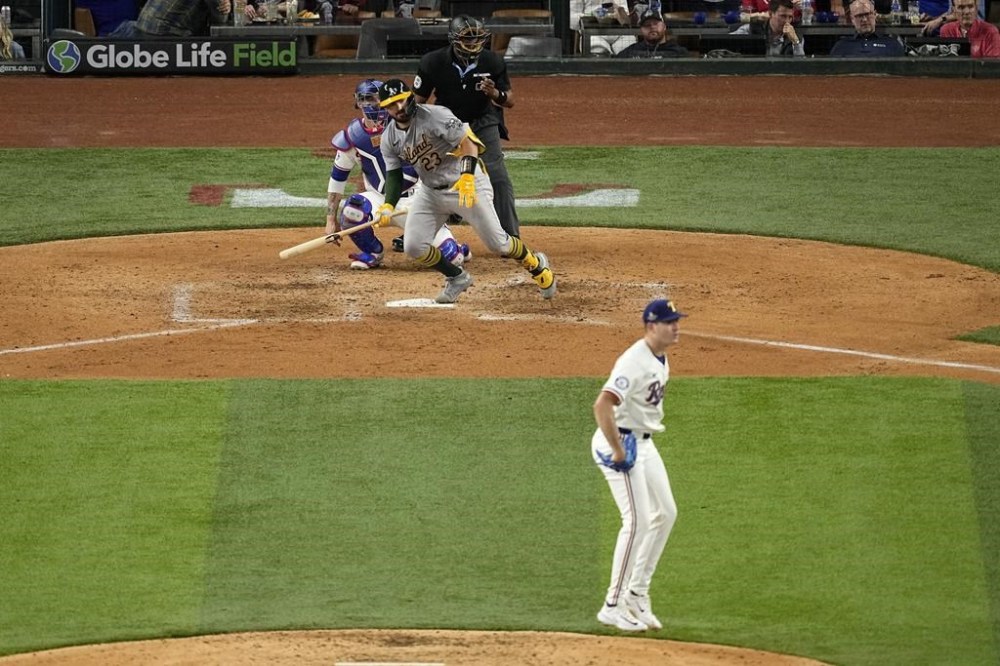 Oakland Athletics' Shea Langeliers sprints out of the batters box on a ground out to third that came off a pitch from Texas Rangers starting pitcher Cody Bradford as catcher Jonah Heim and umpire Ramon De Jesus look on in the sixth inning of a baseball game in Arlington, Texas, Wednesday, April 10, 2024. Bradford and Langeliers were teammates when they played for Baylor university. (AP Photo/Tony Gutierrez)
