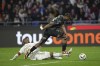 Lyon's Alexandre Lacazette, on the ground, and Reims' Emmanuel Agbadou, challenge for the ball during the French League One soccer match between Lyon and Reims at the Groupama stadium, outside Lyon, France, Saturday, March 30, 2024. (AP Photo/Laurent Cipriani)
