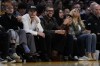 Bad Bunny, center, watches the second half of an NBA basketball game between the Golden State Warriors and the Los Angeles Lakers in Los Angeles, Saturday, March 16, 2024. (AP Photo/Ashley Landis)