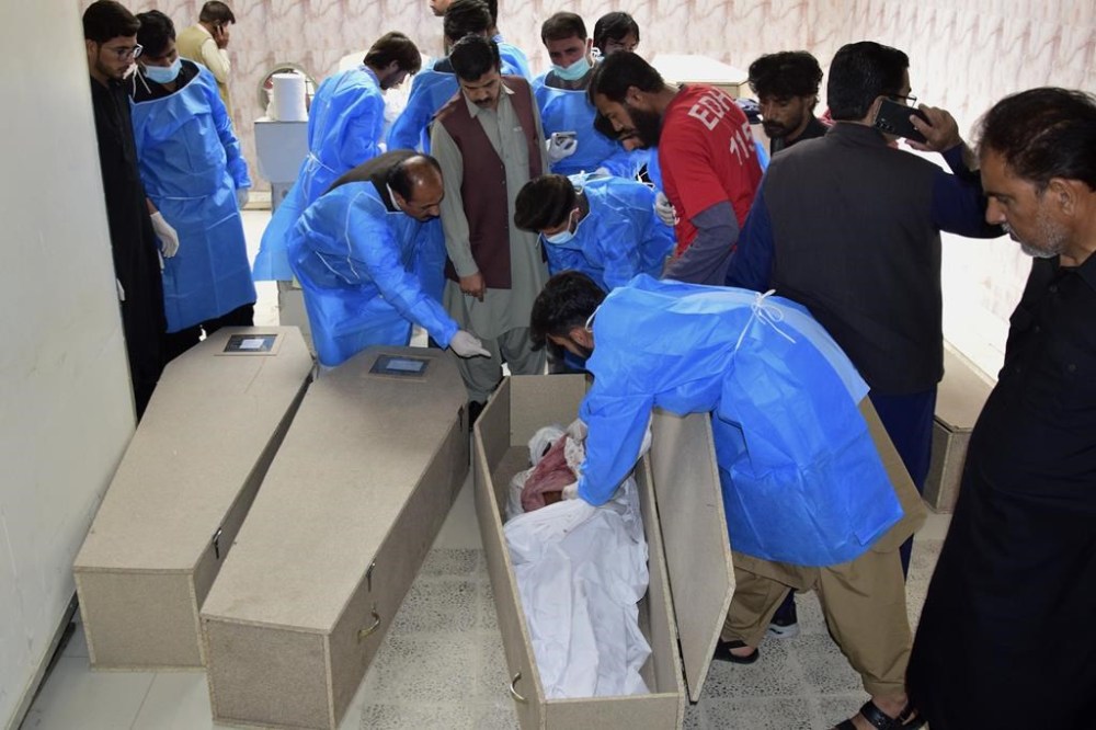 Doctors and other staff examine body of a person, who was killed by gunmen, at a morgue of a hospital in Quetta, Pakistan, Saturday, April 13, 2024. Pakistani police are searching for gunmen who killed eight people after abducting them from a bus on a highway in the country's southwest, a police official said Saturday. Earlier, the same attackers killed two people and wounded six in another car they forced to stop. (AP Photo/Arshad Butt)