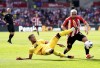Sheffield United's Mason Holgate, left, and Brentford's Neal Maupay challenge for the ball during the English Premier League soccer match between Brentford and Sheffield United at the Gtech Community Stadium in London, Saturday, April 13, 2024. (John Walton/PA via AP)