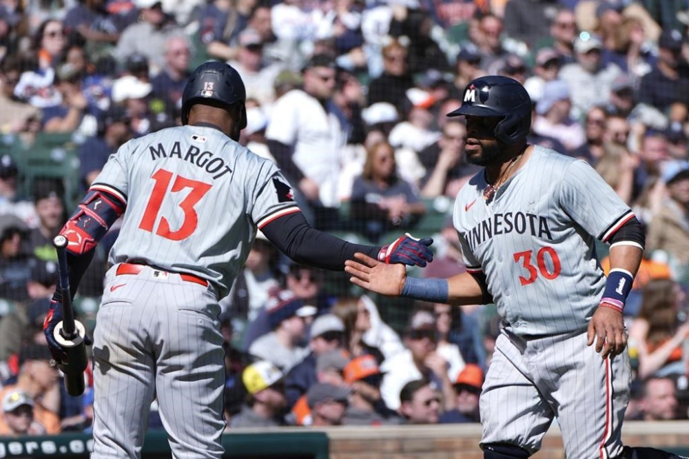 Minnesota Twins' Carlos Santana (30) celebrates scoring with Manuel Margot (13) against the Detroit Tigers in the 11th inning during the first baseball game of a doubleheader, Saturday, April 13, 2024, in Detroit. (AP Photo/Paul Sancya)