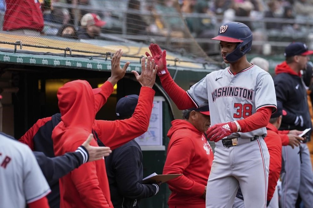 Washington Nationals' Trey Lipscomb (38) celebrates with teammates at the dugout after scoring against the Oakland Athletics on Jacob Young's double during the ninth inning of a baseball game Saturday, April 13, 2024, in Oakland, Calif. (AP Photo/Godofredo A. Vásquez)
