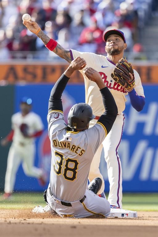Philadelphia Phillies second baseman Edmundo Sosa, top, throws to first as Pittsburgh Pirates' Edward Oliivares (38) slides safely into second on a double during the fourth inning of a baseball game, Saturday, April 13, 2024, in Philadelphia. (AP Photo/Laurence Kesterson)