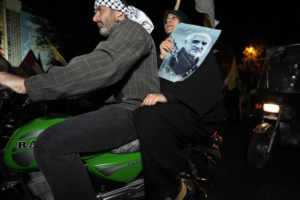 An Iranian demonstrator holds a poster of the late Revolutionary Guard Gen. Mohammad Hadi Haj Rahimi, who was killed in an airstrike widely attributed to Israel that destroyed Iran's Consulate in Syria on April 1, during an anti-Israeli gathering at the Felestin (Palestine) Square in Tehran, Iran, early Sunday, April 14, 2024. Iran launched its first direct military attack against Israel Saturday. (AP Photo/Vahid Salemi)