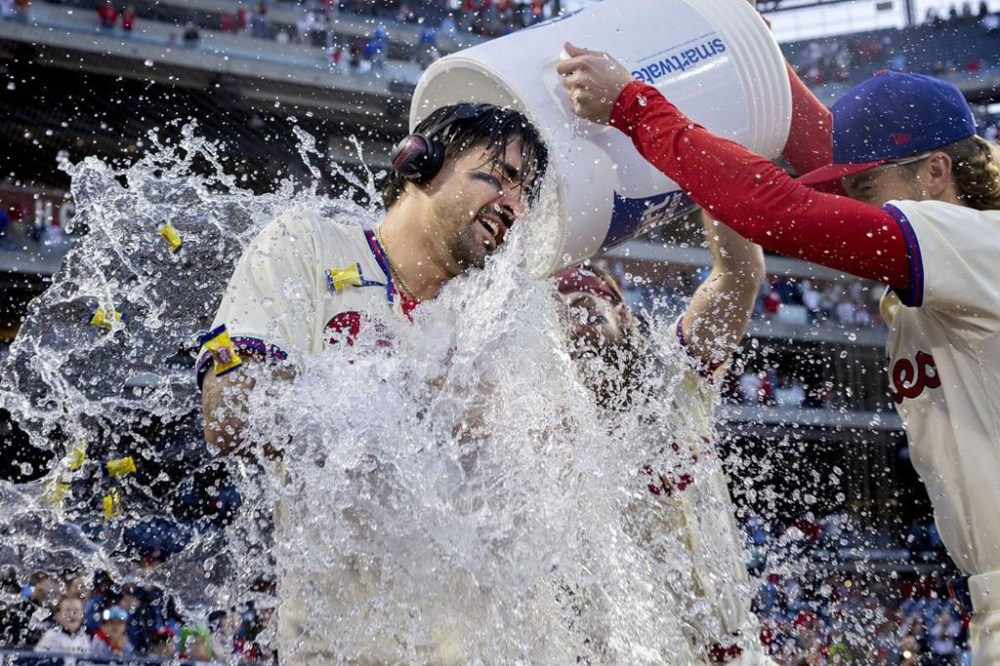 Philadelphia Phillies' Nick Castellanos, left, is doused by teammates Bryson Stott, right, Brandon Marsh, center, after hitting a walkoff single in the ninth inning of a baseball game against the Pittsburgh Pirates, Saturday, April 13, 2024, in Philadelphia. (AP Photo/Laurence Kesterson)