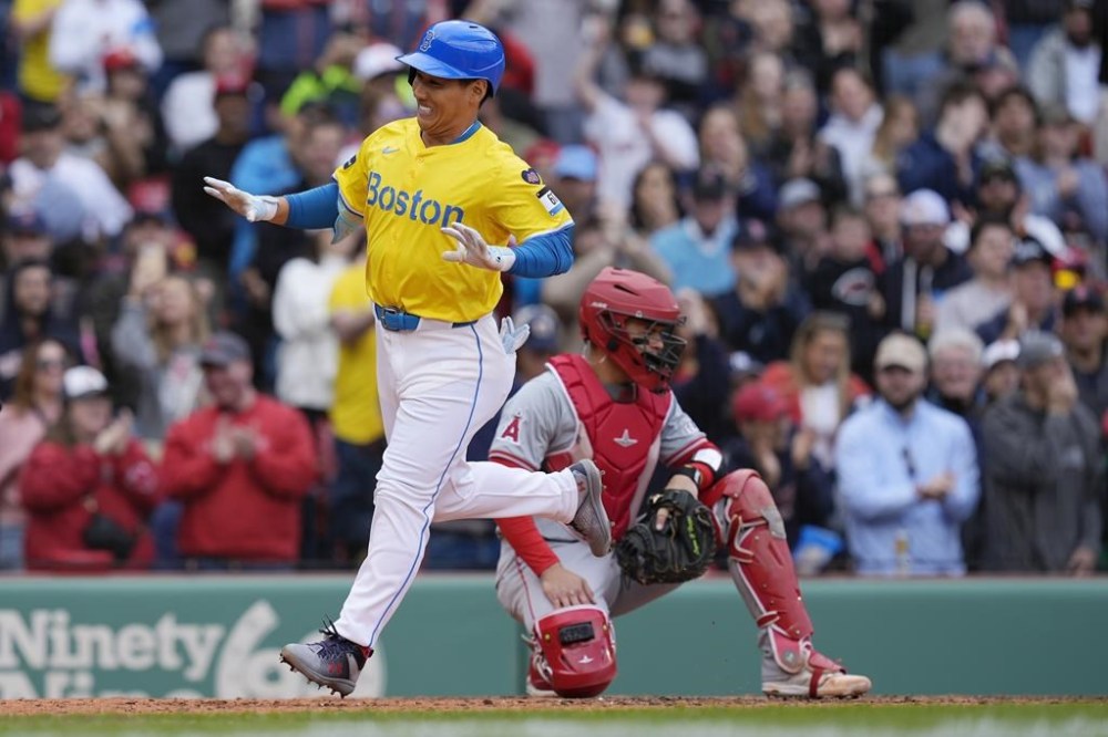 Boston Red Sox's Masataka Yoshida, left, scores on his two-run home run in front of Los Angeles Angels' Logan O'Hoppe, right, during the sixth inning of a baseball game, Sunday, April 14, 2024, in Boston. (AP Photo/Michael Dwyer)