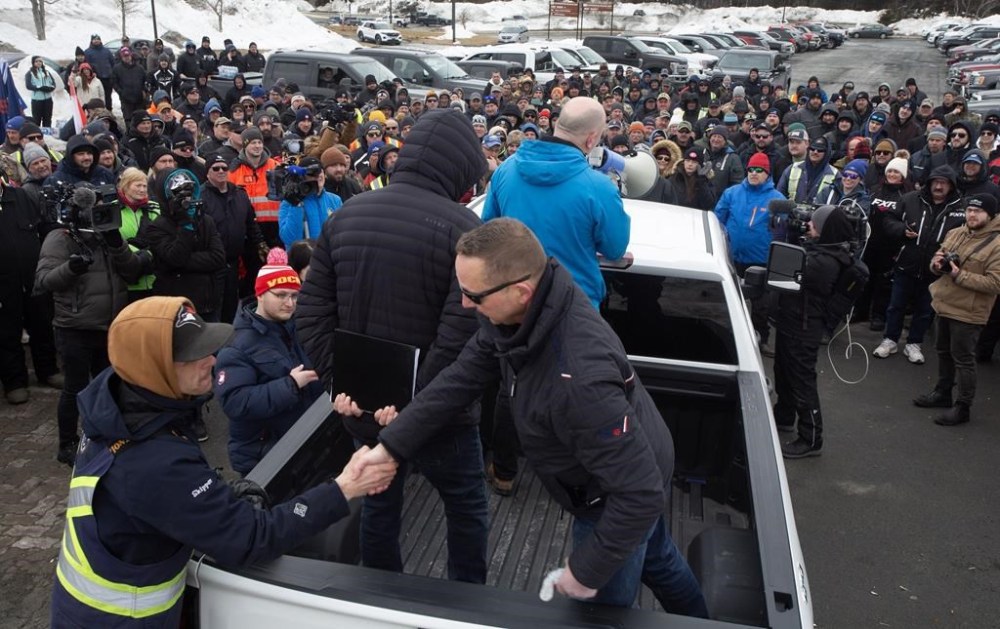 John Efford Jr. shakes hands with a fellow harvester as FFAW Secretary-Treasurer, Jason Spingle addresses the fish harvesters gathered outside the Confederation Building in St. John's, Friday, March 22, 2024. A pricing agreement has been reached between crab fishers and seafood processors that will allow for Newfoundland and Labrador's annual crab fishery to get started. THE CANADIAN PRESS/Paul Daly