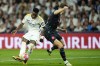 Real Madrid's Vinicius Junior, left, passes the ball past Manchester City's John Stones during the Champions League quarterfinal first leg soccer match between Real Madrid and Manchester City at the Santiago Bernabeu stadium in Madrid, Spain, Tuesday, April 9, 2024. (AP Photo/Jose Breton)