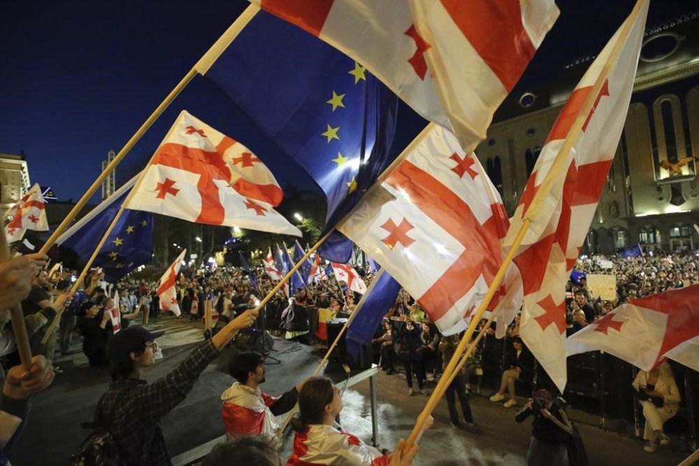 Demonstrators wave Georgian and EU flags as they gather outside the parliament building in Tbilisi, Georgia, on Wednesday, April 17, 2024, to protest against