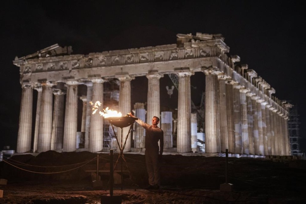 Retired Greek 400-meter hurdles champion Periklis Iakovakis lits a cauldron with the Olympic flame in front of the ancient Parthenon temple at the Acropolis hill, Friday, April 19, 2024. The flame that will burn at the summer Olympics is spending the night at the ancient Acropolis in Athens, a week before its handover to Paris 2024 organizers. (AP Photo/Petros Giannakouris)