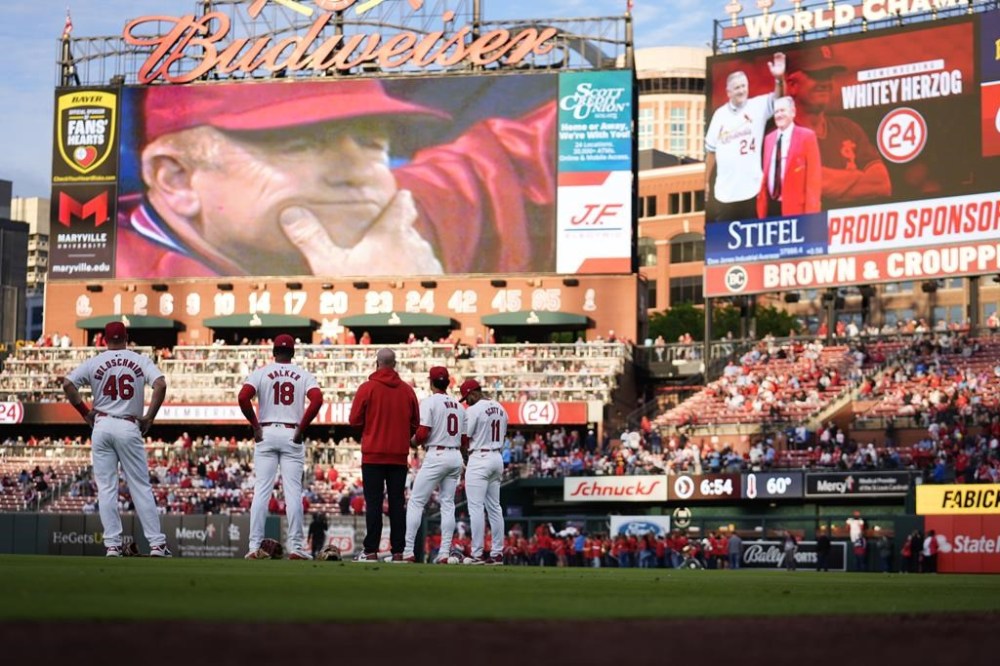 Members of the St. Louis Cardinals pause to watch a video tribute to former Cardinals manager Whitey Herzog before the start baseball game against the Milwaukee Brewers Friday, April 19, 2024, in St. Louis. Herzog, the gruff and ingenious Hall of Fame manager who guided the Cardinals to three pennants and a World Series title in the 1980s, died Monday at the age of 92. (AP Photo/Jeff Roberson)