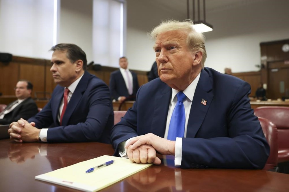 Former president Donald Trump, center, awaits the start of proceedings at Manhattan criminal court, Monday, April 22, 2024, in New York. Opening statements in Donald Trump's historic hush money trial are set to begin. Trump is accused of falsifying internal business records as part of an alleged scheme to bury stories he thought might hurt his presidential campaign in 2016. (AP Photo/Yuki Iwamura, Pool)