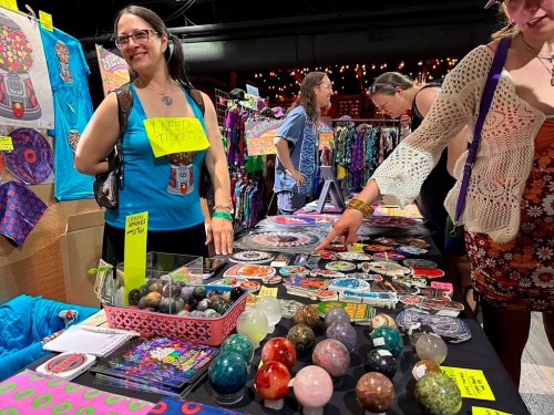 This photo shows Kim Mancini of Reading, Pa. selling Phish inspired posters and stickers during PhanArt on Saturday, April 20, 2024, at the Brooklyn Bowl in Las Vegas. (AP Photo/Josh Cornfield)