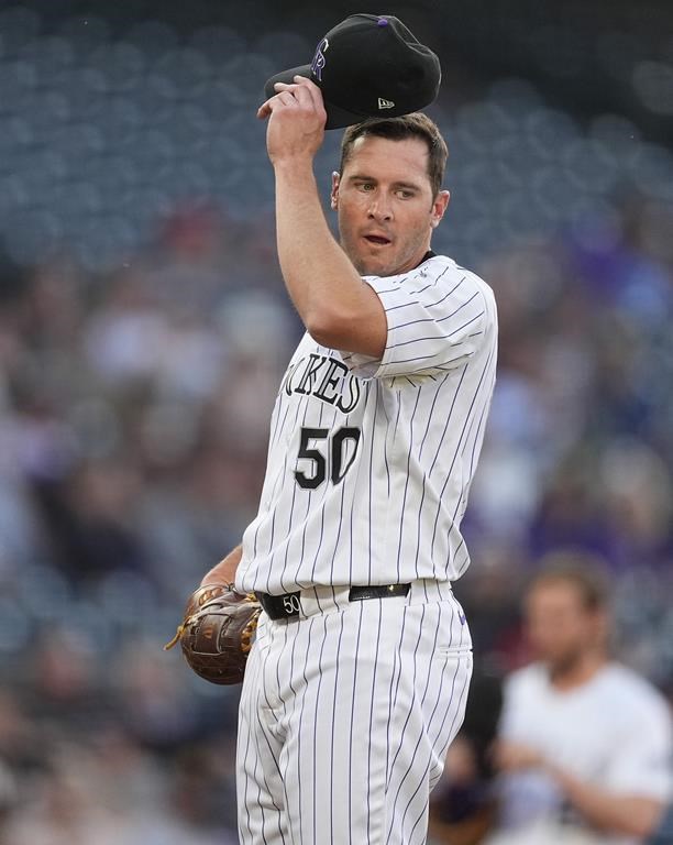Colorado Rockies starting pitcher Ty Blach adjusts his cap as he waits to confer with pitching coach Darryl Scott during the first inning of the team's baseball game against the San Diego Padres on Wednesday, April 24, 2024, in Denver. (AP Photo/David Zalubowski)