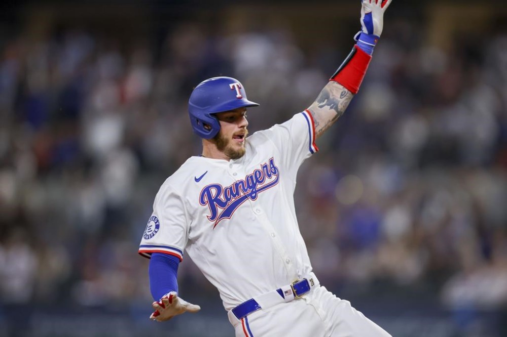 Texas Rangers' Jonah Heim slides into third base after a fielding error by Seattle Mariners right fielder Mitch Haniger during the sixth inning of a baseball game, Wednesday, April 24, 2024, in Arlington, Texas. (AP Photo/Gareth Patterson)