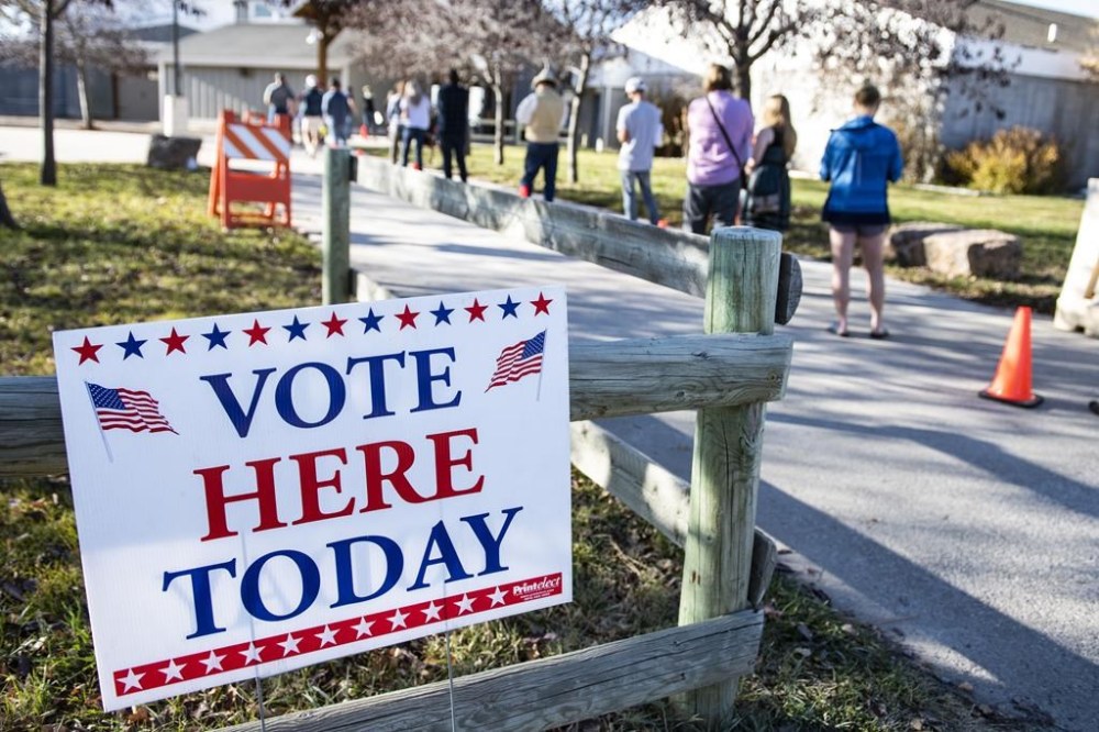 FILE - Patrons of the Gallatin County Fairgrounds wait in line to cast their ballots in Bozeman, Mont., Nov. 3, 2020. A federal judge in Montana has temporarily blocked a law that appeared to require people to cancel any previous voter registrations before signing up to vote in Montana or possibly face criminal charges. An attorney for the plaintiffs said the law wasn't clear about what was required to de-register. (AP Photo/Tommy Martino, file)