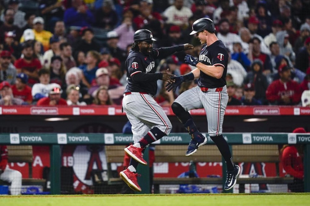 Minnesota Twins' Max Kepler, right, celebrates his solo home run with third base coach Tommy Watkins during the sixth inning of the team's baseball game against the Los Angeles Angels, Saturday, April 27, 2024, in Anaheim, Calif. (AP Photo/Ryan Sun)