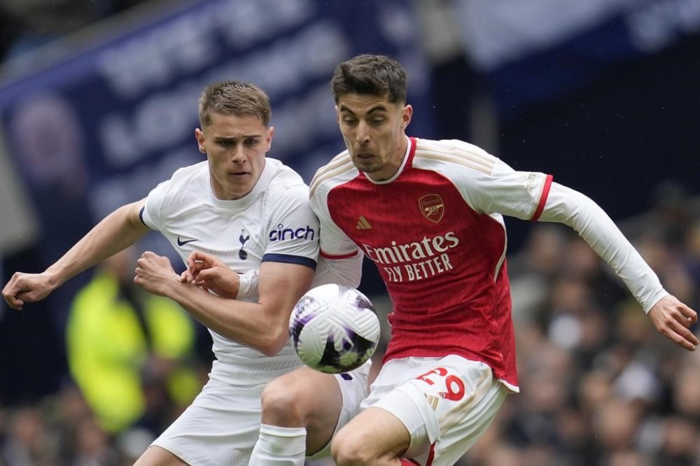 Arsenal's Kai Havertz, right, challenges for the ball with Tottenham's Rodrigo Bentancur during the English Premier League soccer match between Tottenham Hotspur and Arsenal at the Tottenham Hotspur Stadium in London, England, Sunday, April 28, 2024. (AP Photo/Kin Cheung)