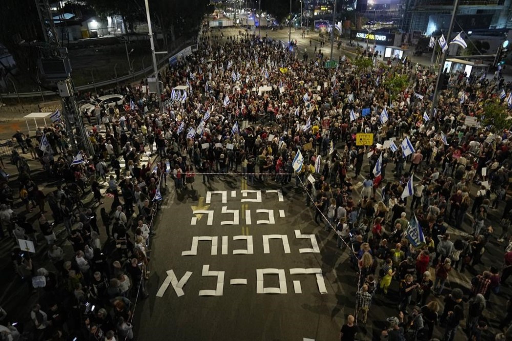People gather next to a sign displayed on the street that reads in Hebrew
