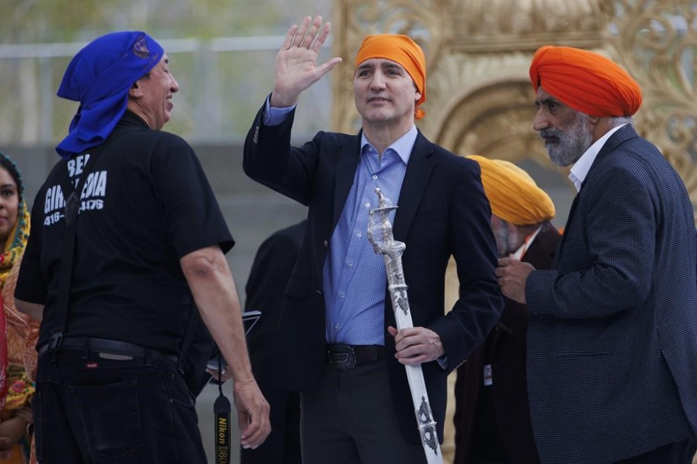 Prime Minister Justin Trudeau waves to the crowd after receiving a ceremonial sabre, called a