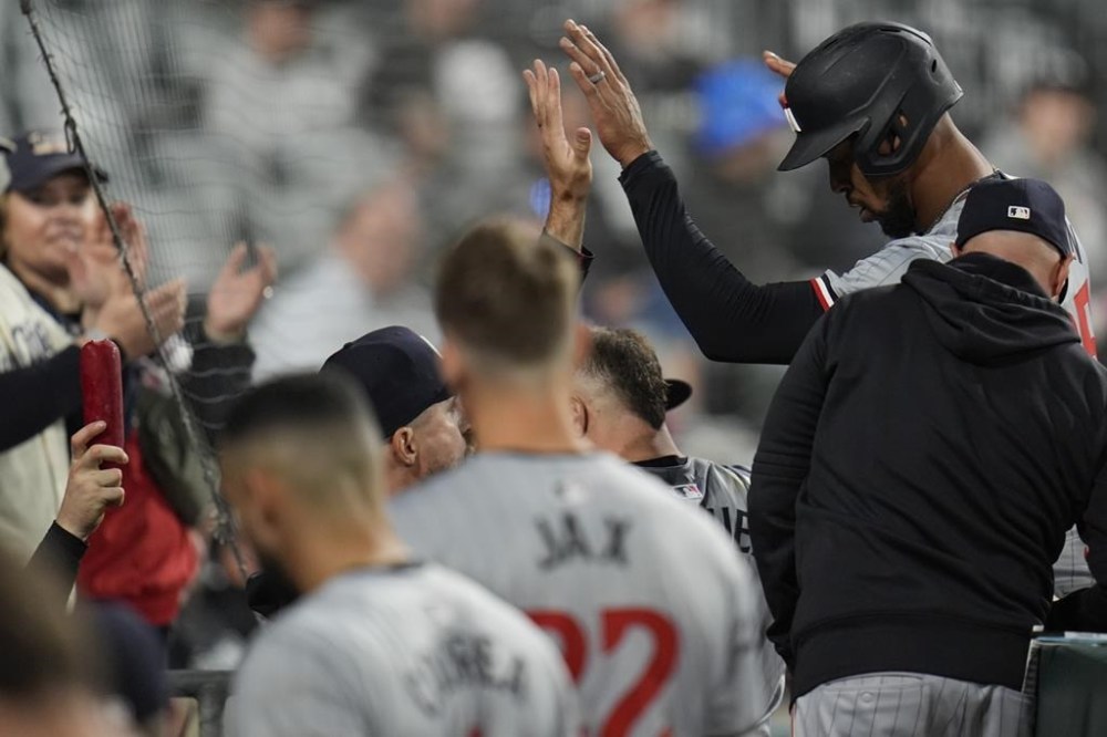 A sausage, left, is held up as Minnesota Twins center fielder Byron Buxton, top right, enters the dugout after scoring on a single by Max Kepler during the ninth inning of a baseball game against the Chicago White Sox, Monday, April 29, 2024, in Chicago. (AP Photo/Erin Hooley)