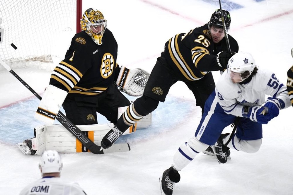 Boston Bruins goaltender Jeremy Swayman (1) fails to make the save on a goal by Toronto Maple Leafs defenseman Jake McCabe during the first period of Game 5 of an NHL hockey Stanley Cup first-round playoff series, Tuesday, April 30, 2024, in Boston. At right trying to clear the crease is Bruins defenseman Brandon Carlo (25) pushing Maple Leafs left wing Tyler Bertuzzi (59). (AP Photo/Charles Krupa)