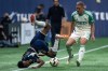 Vancouver Whitecaps' Ali Ahmed (left) falls in front of Austin FC's Alexander Ring (8) as they vie for the ball during the first half of an MLS soccer match in Vancouver, on Saturday, May 4, 2024. THE CANADIAN PRESS/Ethan Cairns