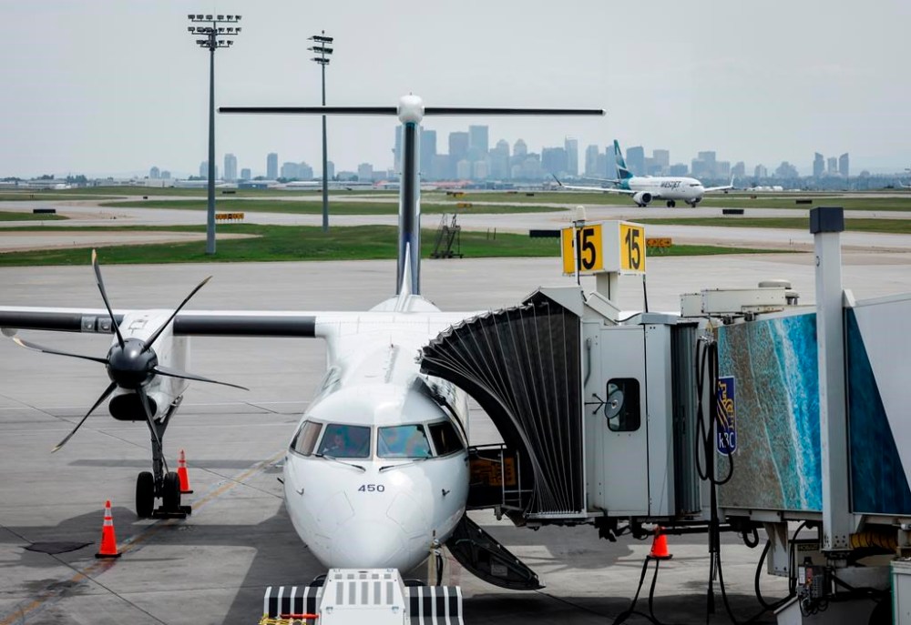 A WestJet passenger jet taxis while a WestJet turbo prop plane sits parked at a departure gate at the Calgary International Airport on Wednesday, May 31, 2023. A statement from the Calgary-based airline says a tentative deal between it and the Aircraft Mechanics Fraternal Association has been agreed to. THE CANADIAN PRESS/Jeff McIntosh