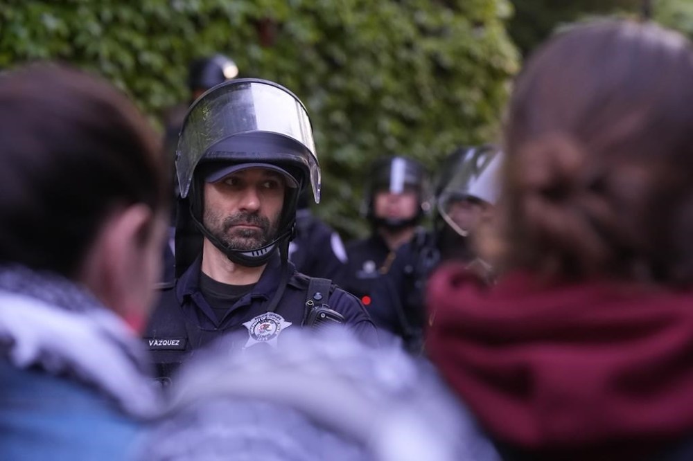 A police officer stands guard blocking pro-Palestinian protesters from returning to their encampment as the encampment is dismantled at the University of Chicago, Tuesday, May 7, 2024. (AP Photo/Charles Rex Arbogast)