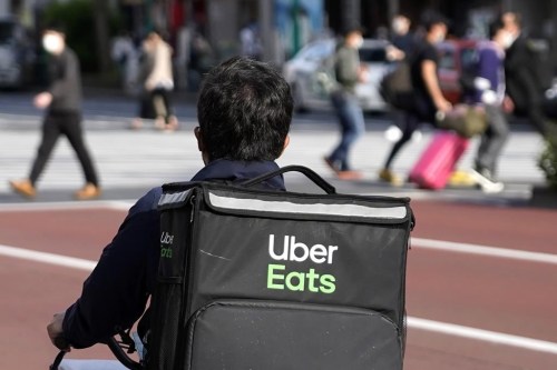 FILE - In this April 28, 2021, file photo, an Uber Eats delivery person rides a bicycle through the Shinjuku district in Tokyo, Japan. Instacart is partnering with Uber Eats to offer restaurant delivery to its customers. Instacart said Tuesday that its U.S. shoppers will see a “Restaurants” tab in the company’s app in the coming weeks. (AP Photo/Shuji Kajiyama, File)