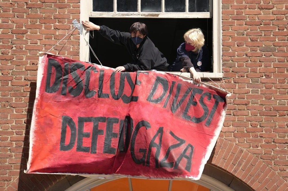 Activists hang a placard from a window of an upper floor of a building at Rhode Island School of Design, Tuesday, May 7, 2024, in Providence, R.I. RISD students and supporters, who have taken over a portion of the building, are demanding that the school condemn Israel's war effort in Gaza, and that the school divest from investments that benefit Israel. (AP Photo/Steven Senne)