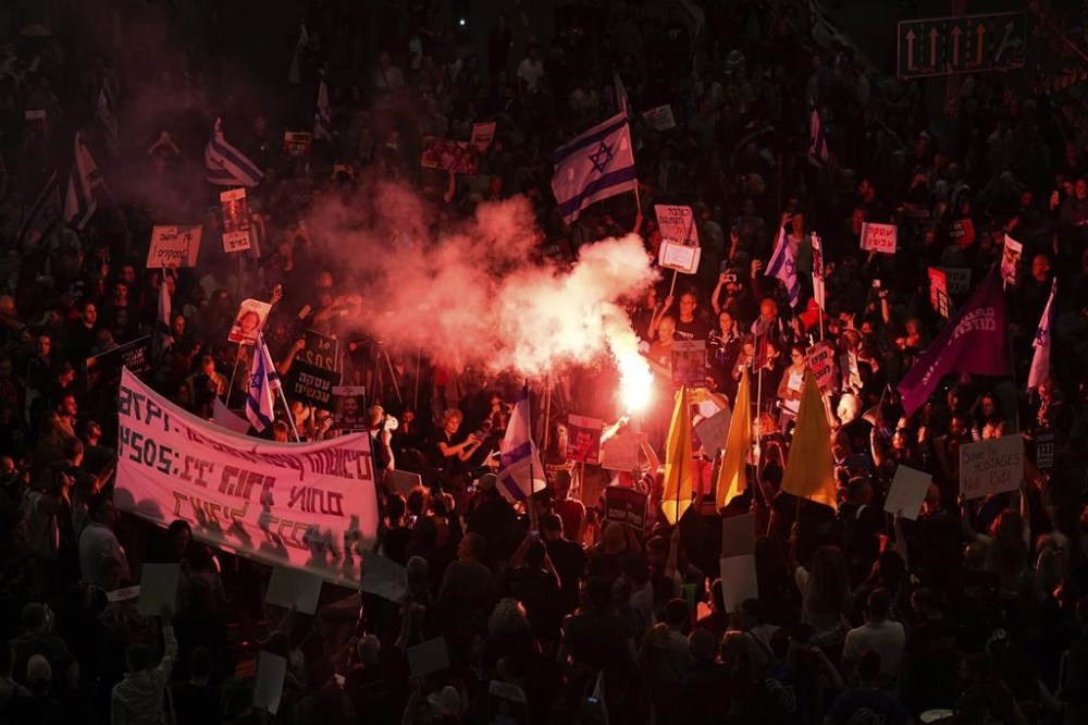 Israeli demonstrators block a road after Hamas's announcement that it has accepted a cease-fire proposal, urging the Israeli government to agree to a deal that would bring home hostages held by the Islamic militant group, in Tel Aviv, Israel, Monday, May 6, 2024. (AP Photo/Ariel Schalit)