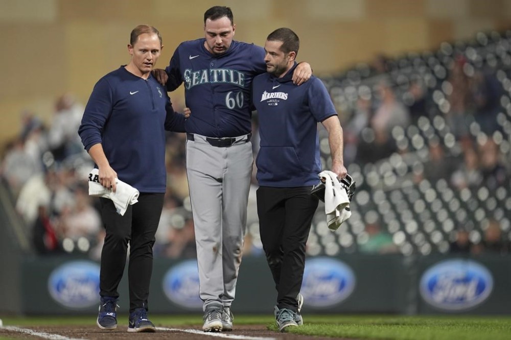 Seattle Mariners relief pitcher Tayler Saucedo (60) walks off the field with trainers after sustaining an injury during the eighth inning of a baseball game against the Minnesota Twins, Tuesday, May 7, 2024, in Minneapolis. (AP Photo/Abbie Parr)